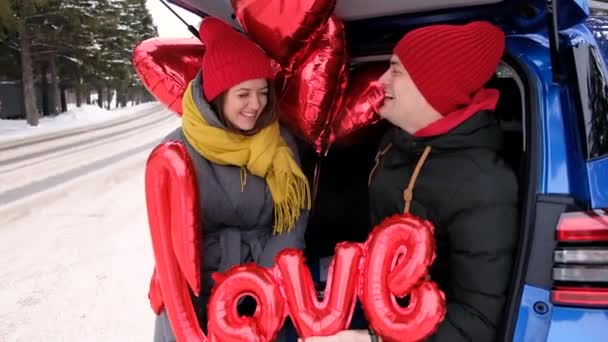 Portrétní šťastní párečkové se na sebe dívají a smějí se. Červené srdce formuje balónky a slovo láska. Svatý Valentýn oslavy, romantické vztahy, upřímné pocity a koncept lásky — Stock video