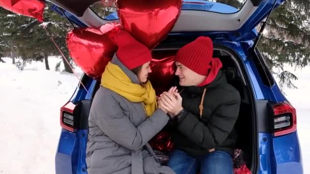 Portrait couple heureux. Petit ami réchauffe doucement les mains de sa petite amie, en regardant dans les yeux. Ballons rouges en forme de coeur sur le fond. Fête de la Saint-Valentin, relations romantiques, concept d'amour. — Video