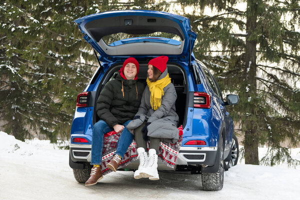 Romantic young hipster couple hugging while sitting in car trunk. Love, valentines and holiday concept. Kiss and hug. Valentines day celebration and happiness concept