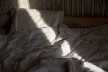 Güneş ışığı yatağa düşer. Sabah güneş pencereden içeri doğru ışıldar. Sıcak Güneş Işığıyla Yeni Gün.