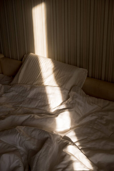 Sunbeam falls on the bed. The sun rays through window in the morning. New Day with Warm Sunlight Flare.