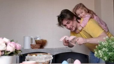 Paskalya, aile, tatil ve çocuk konsepti. Tavşan kulaklı baba paskalya tavşanı gibi oynuyor, kızıyla zıplıyor. Mutlu aile Paskalya için hazırlanıyor.