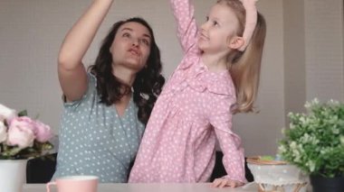 Paskalya, aile, tatil ve çocuk konsepti. Anne ve kızı Paskalya yumurtalarıyla oynuyorlar. Mutlu aile Paskalya için hazırlanıyor.