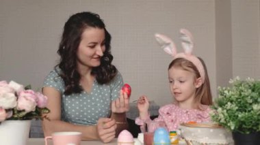 Paskalya, aile, tatil ve çocuk konsepti. Anne ve kızı yumurta boyuyor. Mutlu aile Paskalya için hazırlanıyor.