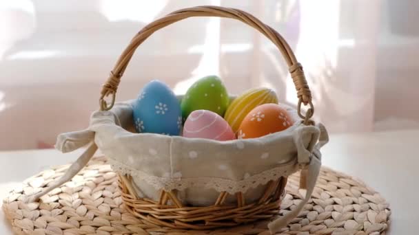 Kobiece ręce biorą wielkanocne kolorowe jajka z kosza na białym drewnianym stole. Szczęśliwego Wielkanocnego tła. — Wideo stockowe