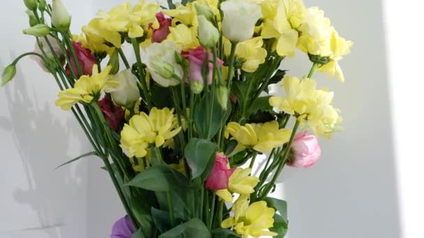Oeufs colorés de Pâques dans un panier sur une table en bois blanc. Bouquet de fleurs jaunes sur fond. Joyeux Pâques. Humeur printanière. — Video