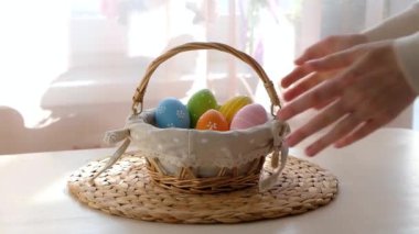 Kadın eli, beyaz ahşap masadan içinde Paskalya yumurtaları olan sepeti alır. Mutlu Paskalyalar.