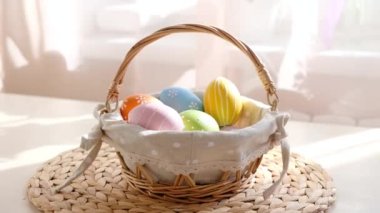 Kadın eli, beyaz ahşap masadaki sepetten Paskalya renkli yumurtaları alır. Mutlu Paskalyalar.