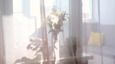 Evdeki vazoda bahar çiçekleri. Yaz baharı, mutlu yaşam konsepti. Rüzgâr perdeleri sallıyor.