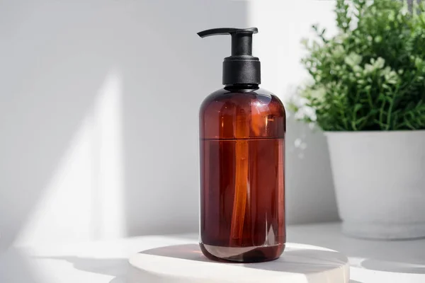 Brown glass bottle on white background in the morning rays of light. Eco cosmetic cream, serum for skin, face and body. Concept of skincare, spa and wellness center. Natural beauty products