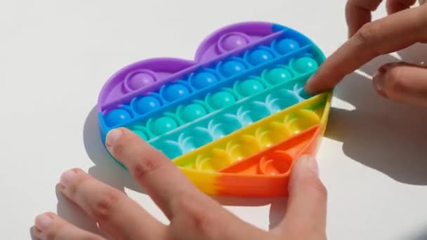 Hände spielen mit Antistress Pop it Spielzeug. Regenbogen sensorische Fidget isoliert auf weißem Hintergrund. Neues trendiges Silikonspielzeug. — Stockvideo