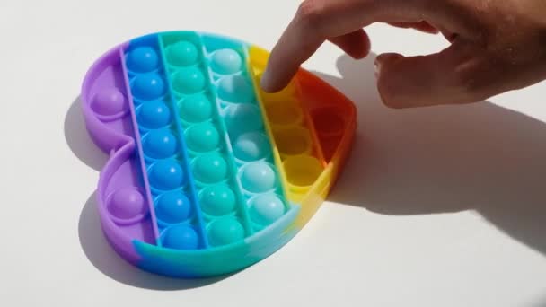 Handen spelen met antistress pop het speelgoed. Regenboog zintuiglijke fidget geïsoleerd op witte achtergrond. Nieuw trendy siliconen speelgoed. — Stockvideo