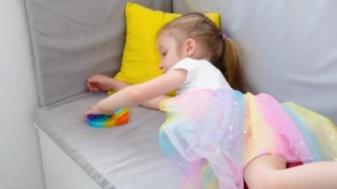 Stres önleyici oyuncağı patlat. Gökkuşağı duyusal hareketlerle oynayan kız beyaz arka planda izole edilmiş. Yeni moda silikon oyuncak.