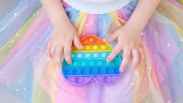 Antystresowa zabawka. Dziewczyna bawiąca się tęczowym fidget sensorycznym izolowane na białym tle. Nowa modna silikonowa zabawka. — Wideo stockowe