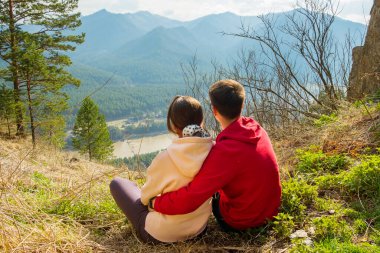 Genç gezgin çift dinleniyor ve dağlarda selfie çekiyor. Erkek ve kadın güzel kayalık bir patikada sırt çantalarıyla yürüyüş yapıyorlar. Aile seyahati ve macera konsepti