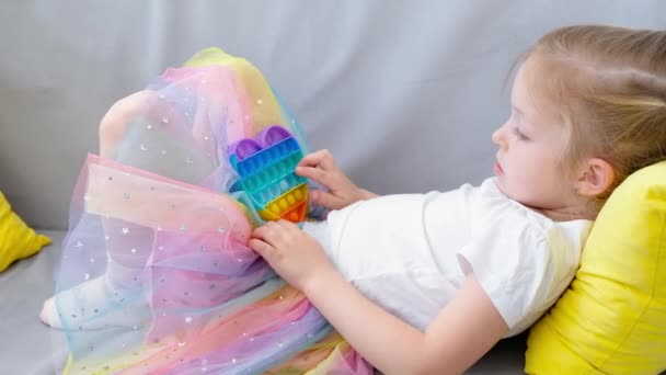 Antistress spräcker leksaken. Flicka leker med regnbåge sensoriska fidget isolerad på vit bakgrund. Ny trendig silikonleksak. — Stockvideo