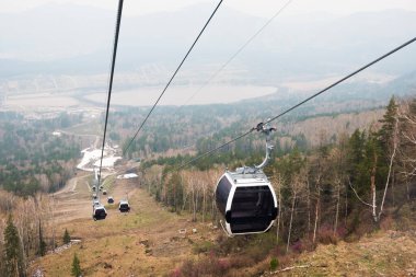 Dağ kayak merkezindeki asansör kabinleri. Bulutlu bir günde Hilghland Dağı 'nda kayak kaldırma halatı. Kayak teleferiği kablosu insanlarla dolu. Manzaralı, yokuş aşağı geniş bir manzara..