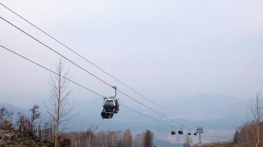 Dağ kayak merkezindeki asansör kabinleri. Bulutlu bir günde Hilghland Dağı 'nda kayak kaldırma halatı. Kayak teleferiği kablosu insanlarla dolu. Manzaralı, yokuş aşağı geniş bir manzara..