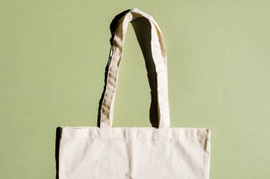 Yeşil ve bej arka planda tekrar kullanılabilir pamuk alışveriş torbası. Sıfır atık. Plastik yok