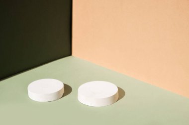Geometrik formlarla soyut asgari sahne. Yeşil ve bej arkaplanlı silindir podyumlar. Soyut arkaplan. Kozmetik kapsülleri göstermek için sahne. Vitrin, vitrin. 3d hazırlayıcı.