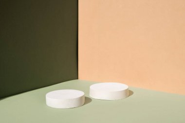Geometrik formlarla soyut asgari sahne. Yeşil ve bej arkaplanlı silindir podyumlar. Soyut arkaplan. Kozmetik kapsülleri göstermek için sahne. Vitrin, vitrin. 3d hazırlayıcı.
