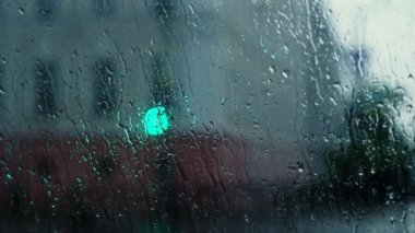  Yağmur Damlaları bokeh ışık efektleriyle pencereye düşüyor. Araba sürerken sağanak yağmur, arka planda bulanıklık. Yağmur damlaları damlıyor