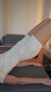 Kadın, ıslah yatağında pilates eğitiyor. Beden eğitimi için pilates stüdyosu makinesi. Formda, sağlıklı ve güçlü özgün bir vücut. Fitness konsepti. 