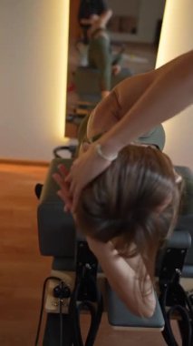 Jimnastik salonunda reformist bir makinede pilates yapan genç bir kadın. Fitness ve sağlık odaklı egzersiz.