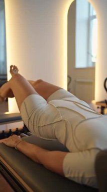 Kadın, ıslah yatağında pilates eğitiyor. Beden eğitimi için pilates stüdyosu makinesi. Formda, sağlıklı ve güçlü özgün bir vücut. Fitness konsepti. 