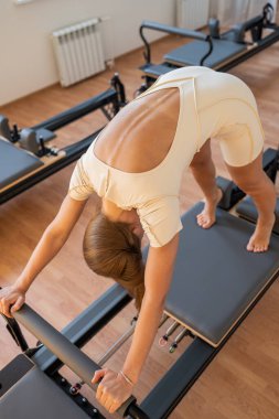 Bireysel pilates oturumu, kontrollü nefes alma ve titiz bir şekilde diz arkası gerilmesini gösteriyor.