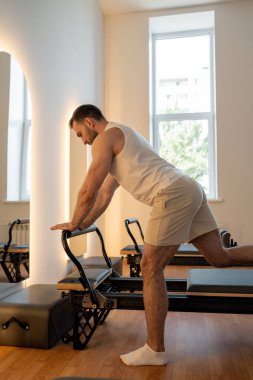 Adam ıslah yatağında pilates eğitiyor. Beden eğitimi için pilates stüdyosu makinesi. Formda, sağlıklı ve güçlü özgün bir vücut. Fitness konsepti. 