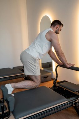 Adam ıslah yatağında pilates eğitiyor. Beden eğitimi için pilates stüdyosu makinesi. Formda, sağlıklı ve güçlü özgün bir vücut. Fitness konsepti. 