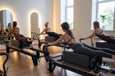 Beden eğitimi öğretmenleri pilates egzersizleri yaparken yenilikçi yataklar ve direniş bantları kullanarak sağlıklı yaşam tarzını ve çekirdek kuvvetlendirmeyi teşvik ediyorlar. Yüksek kalite fotoğraf