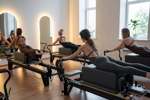 Beden eğitimi öğretmenleri pilates egzersizleri yaparken yenilikçi yataklar ve direniş bantları kullanarak sağlıklı yaşam tarzını ve çekirdek kuvvetlendirmeyi teşvik ediyorlar. Yüksek kalite fotoğraf