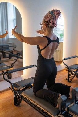 Pilates antrenmanı sırasında odaklanmış bir kadınla ev stüdyosu kurmak.