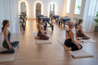 Stüdyoda oturan, odaklanmış, aynalı duvar ve ışıkla dans eden bir kadın.