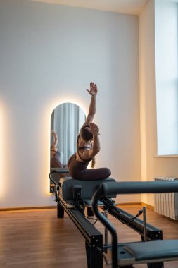 Siyah spor giysili formalı kadınlar pilates yan dirsek egzersizleri yapıyorlar. Minimum parlak modern stüdyoda pilates reformatlı makine yatağı üzerinde. - Evet. Yüksek kalite fotoğraf