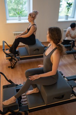 Mutlu ve yorgun kadın pilates çalışmasından sonra dinleniyor. Yorgun ve yorgun bayan sporcu ıslah yatağında oturuyor.