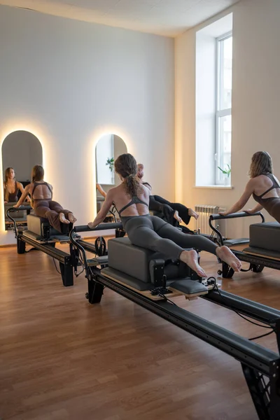 Beden eğitimi öğretmenleri pilates egzersizleri yaparken yenilikçi yataklar ve direniş bantları kullanarak sağlıklı yaşam tarzını ve çekirdek kuvvetlendirmeyi teşvik ediyorlar. Yüksek kalite fotoğraf