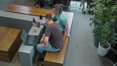 In a cozy workspace, two men are deeply engaged in a thoughtful discussion while reviewing a laptop screen