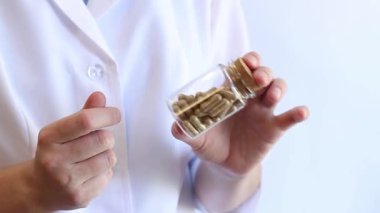 Doktorun elinde bir kavanoz ilaç var. Tabletler, cam kavanozdaki kapsüller eczacının elinde. İlaçlar ya da diyet takviyeleriyle ellerinizi yakın tutun. Beyaz önlüklü doktor. İlaç.