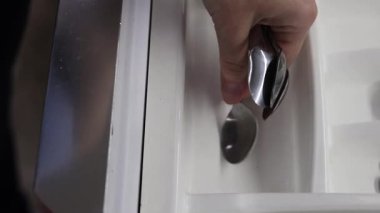 Çay kaşıklarını mutfak çatal bıçakları düzenleyicisine katlıyorum. Temiz kaşıklar çatal bıçak tepsisine konur, yakın plan. Mutfak eşyaları.