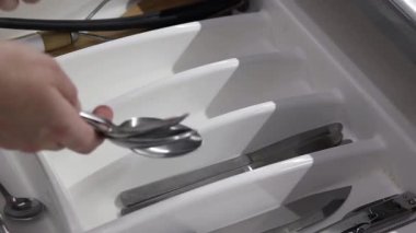 Çatal bıçak takımını mutfak düzenleyicisine katlıyorum. Temiz kaşıklar ve çatallar katlanmış çatal bıçak tepsisine konur, yakın plan. Mutfak eşyaları.