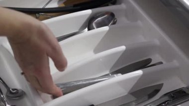 Çatal bıçak takımını mutfak düzenleyicisine katlıyorum. Temiz kaşıklar ve çatallar katlanmış çatal bıçak tepsisine konur, yakın plan. Mutfak eşyaları.