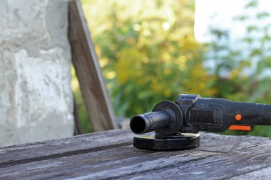 Cordless angle grinder on a wooden table. Tool for repair and construction. Cordless angle grinder close-up. Tool in the country