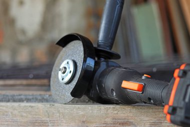 Cordless angle grinder on a wooden table. Tool for repair and construction. Cordless angle grinder close-up. Tool in the country