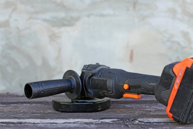 Cordless angle grinder on a wooden table. Tool for repair and construction. Cordless angle grinder close-up. Tool in the country
