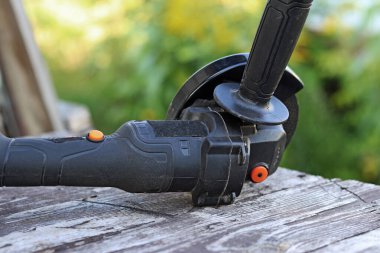 Ahşap bir masanın üzerinde kablosuz açı öğütücü. Tamir ve inşaat için bir araç. Kablosuz açı öğütücü yakın plan. Ülkedeki araç.