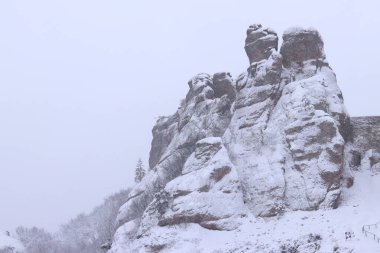Karla kaplı Belogradchik kayaları. Bulgaristan. Kış havasında olağandışı şekillerde kaya oluşumları. Kar yağışı. Doğal dönüm noktası. Belogradchik şehri yakınlarındaki kayalar. Doğa