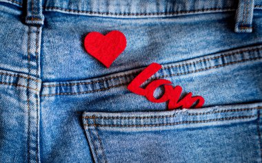 Kırmızı keçeli kalp ve kot pantolonun cebinde aşk kelimesi. Romantik Sevgililer Günü konsepti. Üst Manzara. Seçici odak.